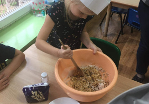 Dziewczynka miesza owsianą masę w misce.