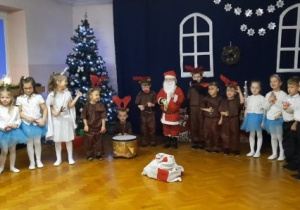 Dzieci ustawione w półkolu grają na instrumentach.