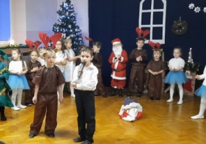 Chłopiec śpiewa kolędę, a reszta grupy ustawiona w półkolu.