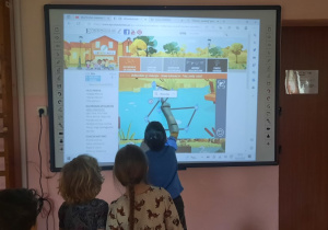 Dziecko wykonuje zadanie na tablicy multimedialnej.