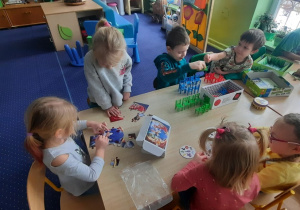 Dzieci przy stolikach grają w gry planszowe.