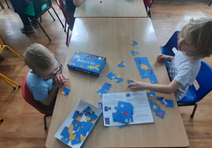 Dzieci przy stolikach grają w gry planszowe.