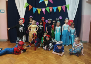 dzieci w przebraniach stoją na sali gimnastycznej i pozują do zdjęcia
