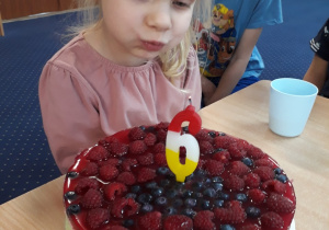 Dziewczyna dmucha świeczki.