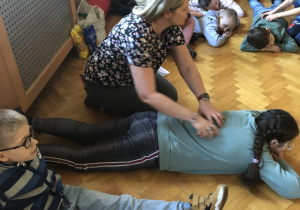 W parach. Jedna osoba leży na brzuchu, druga wykonuje masażyk.