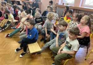 Dzieci siedzą i słuchają koncertu.