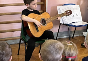 Chłopiec próbuje grać na gitarze.