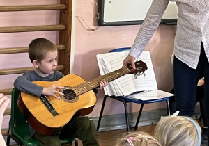 Chłopiec próbuje grać na gitarze.