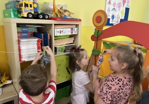 Dzieci wieszają skarpetki na sznurku wykorzystując klamerki.