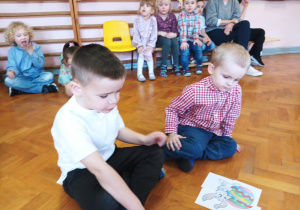 dzieci siedzą na podłodze sali gimnastycznej, układają obrazek