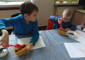 dzieci przy dużym stole wkładają kolorowe kulki soczewicy do żółtego wagonika