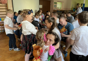Dzieci wręczają dzieciom prezenty i składają życzenia.