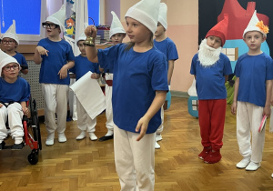 Smerfy ustawione w półkolu, Harmoniusz dzwoni dzwoneczkiem.