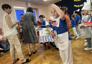 Dziewczynka pokazuje co otrzymała na zakończenie roku.