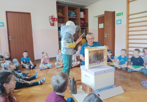 dzieci zebrane na sali gimnastycznej oglądają ul i domek dla pszczół