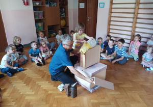 dzieci zebrane na sali gimnastycznej oglądają ul i domek dla pszczół