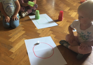 Dzieci siedzą na podłodze i obserwują jadącego ozobota.