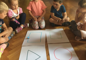 Dzieci siedzą na podłodze i obserwują jadącego ozobota.