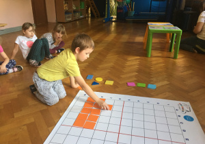 Dzieci tworzą obrazek na macie zgodnie z kodem.