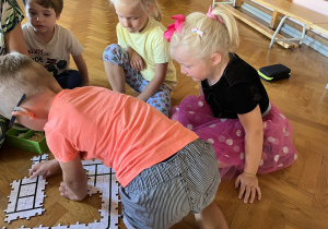 Dzieci siedzą na podłodze i układają drogę z puzzli dla ozobota.