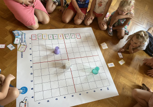 Dzieci siedzą na podłodze i obserwują jazdę genibota.