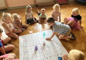 Dzieci siedzą na podłodze i kodują drogę genibota.