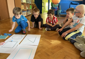 Dzieci siedzą na podłodze i obserwują jazdę ozobota.