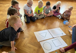 Dzieci siedzą na podłodze i obserwują jazdę ozobota.