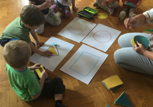 Dzieci siedzą na podłodze i obserwują jazdę ozobota.