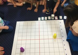 Dzieci siedzą na dywanie i programują genibota.