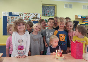 dziewczynka świętuje urodziny, dzieci stoją dookoła niej i składają jej życzenia