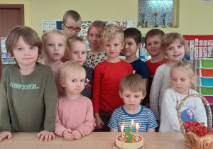 chłopiec świętuje urodziny, dzieci stoją dookoła niego i składają mu życzenia