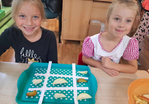 Dzieci siedzą przy stoliku i układają owocowe sudoku.