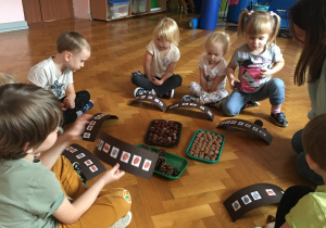 Dzieci siedzą na podłodze i układają rytmy.