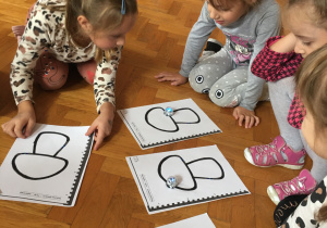 Dzieci siedzą na podłodze i obserwują ozobota.