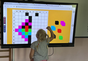 Dziecko wykonuje zadanie na tablicy multimedialnej.