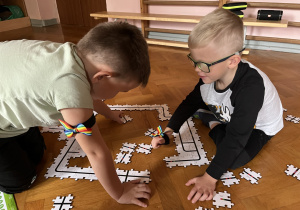 Dzieci wykonują drogę z puzzli dla ozobota.
