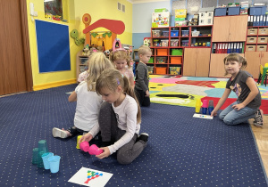 Dzieci wykonują zadanie z kolorowymi kubeczkami.