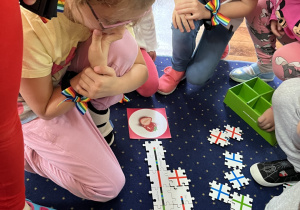Dzieci siedzą na dywanie i układają drogę z puzzli dla ozobota.