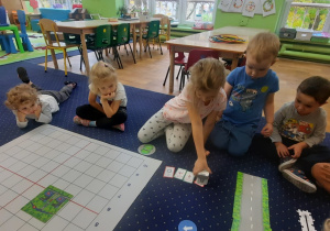 Dzieci wykonują zadanie na macie do kodowania.