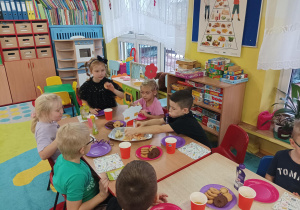 dzieci przy stolikach świętują urodziny koleżanki