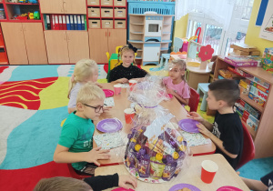 dzieci przy stolikach świętują urodziny koleżanki