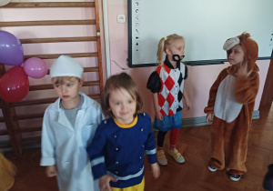 dzieci w przebraniach karnawałowych tańczą na balu przebierańców, na sali gimnastycznej