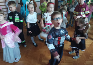 dzieci w przebraniach karnawałowych tańczą na balu przebierańców, na sali gimnastycznej