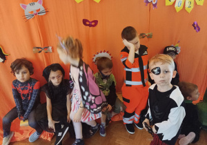 dzieci w przebraniach karnawałowych tańczą na balu przebierańców, na sali gimnastycznej