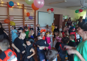 dzieci w przebraniach karnawałowych tańczą na balu przebierańców, na sali gimnastycznej