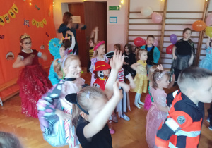 dzieci w przebraniach karnawałowych tańczą na balu przebierańców, na sali gimnastycznej