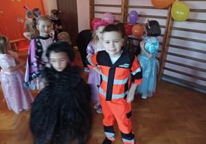 dzieci w przebraniach karnawałowych tańczą na balu przebierańców, na sali gimnastycznej