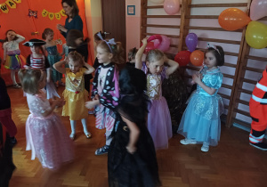 dzieci w przebraniach karnawałowych tańczą na balu przebierańców, na sali gimnastycznej