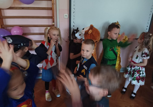 dzieci w przebraniach karnawałowych tańczą na balu przebierańców, na sali gimnastycznej